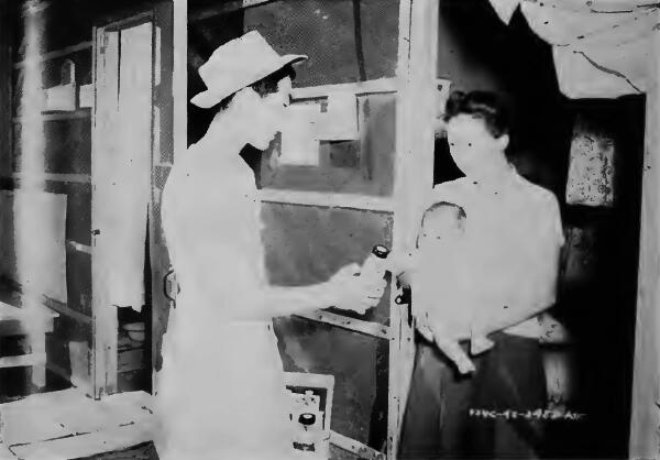 An evacuee messenger delivering a bottle of baby formula to a mother at Fresno (California) Assembly Center