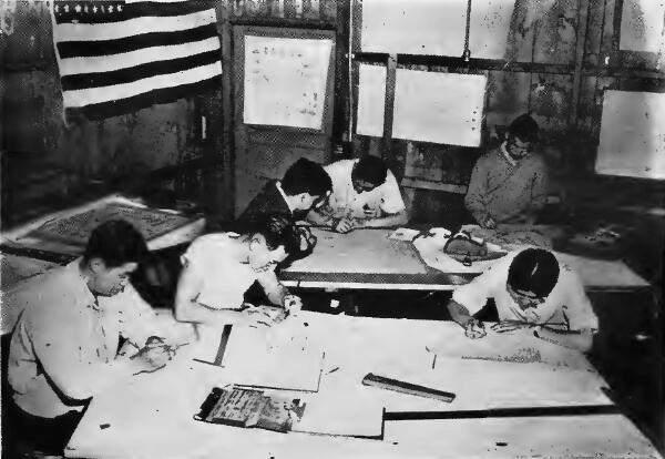 A group of evacuees busy in a drafting room of an Assembly Center